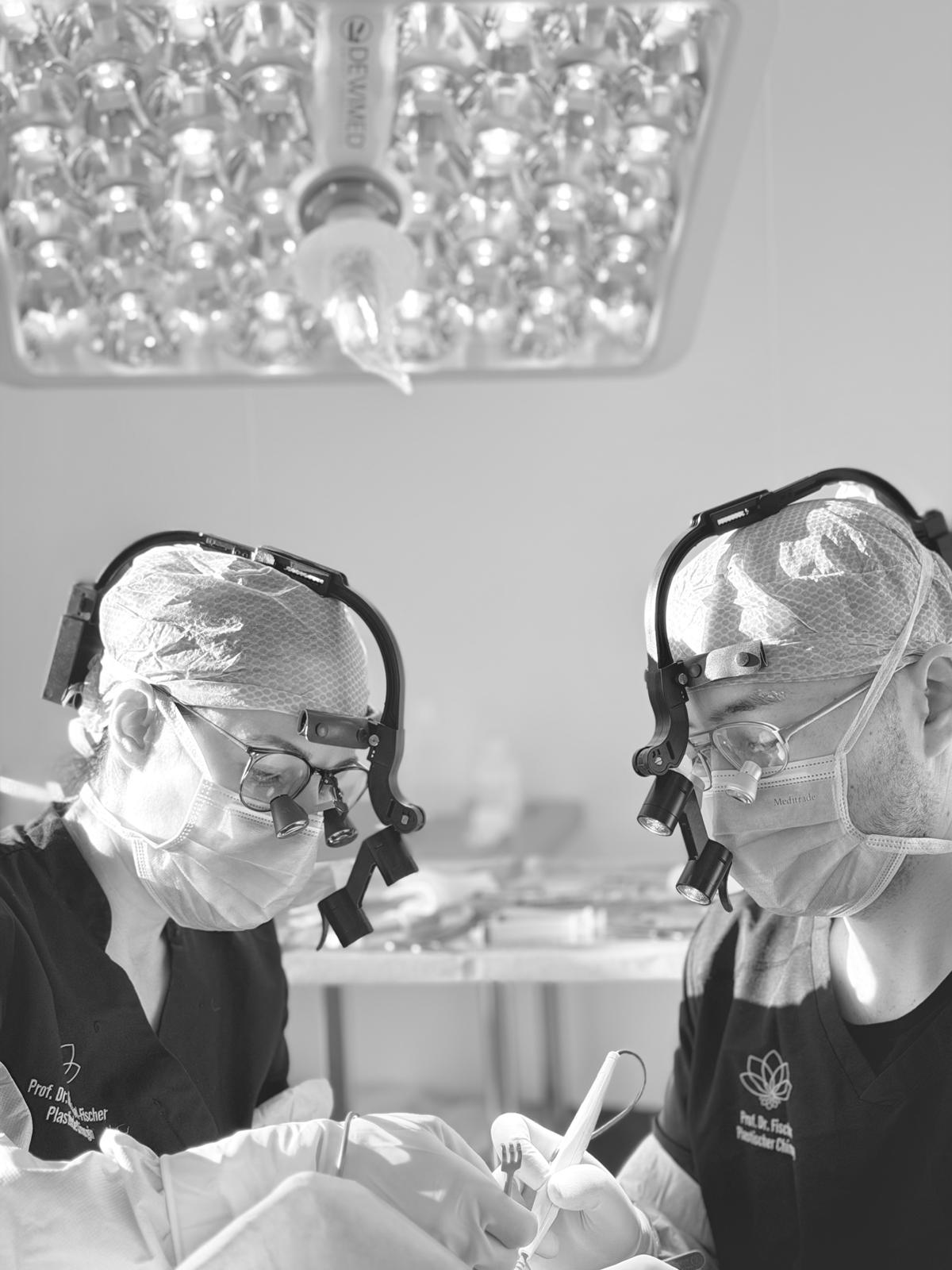 Zwei Fachärzte für Plastische und Ästhetische Chirurgie operieren gemeinsam mit Lupenbrille im AESTHETIKON Heidelberg